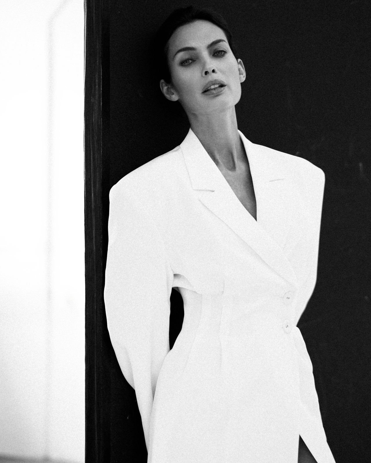 Natalia Boykova, white blazer against a dark wall